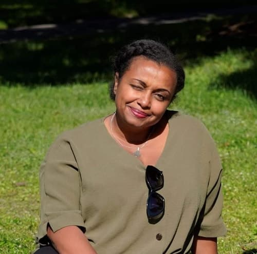 Nainen istuu nurmikolla