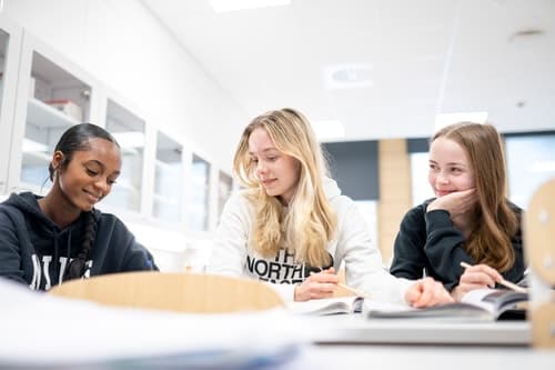 Koululaiset tekevät tehtäviä pöydän ääressä